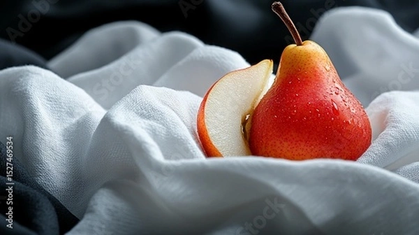 Fototapeta Red pear on white fabric with a slice