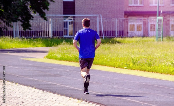 Fototapeta A man runs through the stadium
