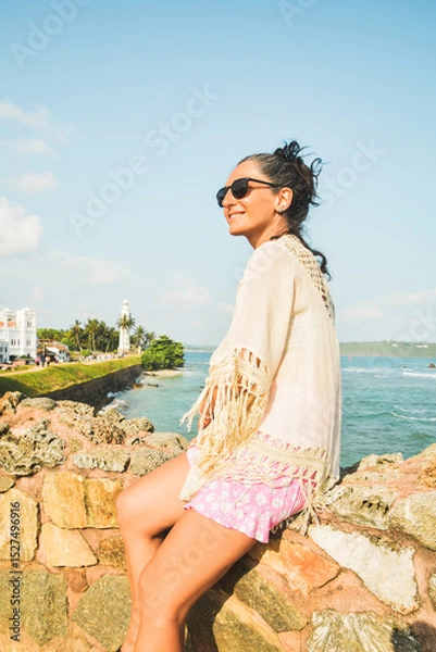 Fototapeta Woman tourist sit enjoy panoramic Lookout from UNESCO Galle Fort. Galle Fort Walk with Ocean Views concept. Sightseeing landmark and popular visit destination in Sri lanka