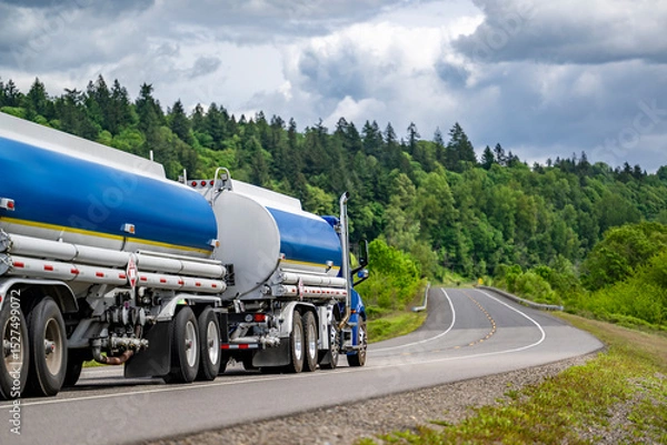 Obraz Day cab blue big rig semi truck tractor transporting fuel in two tank semi trailers running on the winding highway road