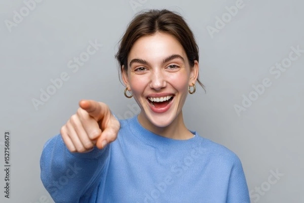Obraz Young woman pointing at camera with cheerful expression