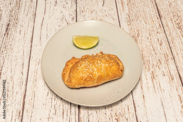 Fototapeta "empanada" as we know it today, with its distinctive crescent or round shape and scalloped edge, has its most direct origins in the Mediterranean region