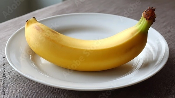 Fototapeta A single ripe banana placed on a white plate