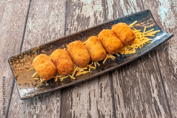 Fototapeta The outer layer, usually breadcrumbs, should be golden, fine, and exceptionally crispy to the bite. This textural contrast is critical to the croquette experience