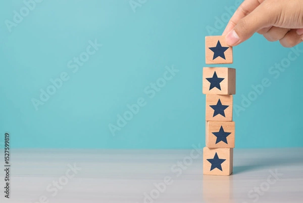 Obraz Hand placing wooden blocks with star icons to represent increasing rating, ranking, and customer satisfaction, with copy space. Ideal for business, review systems, and service quality.