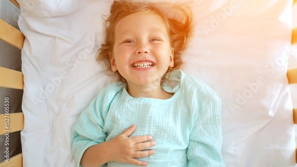 Fototapeta Happy child smiling and lying on bed in hotel room
