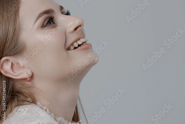 Fototapeta Portrait of a woman smiling softly against a neutral background during a modern photography session in a studio setting