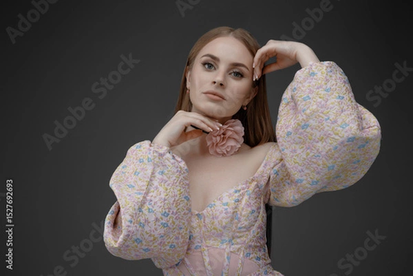 Fototapeta Model poses elegantly while showcasing a floral accessory in a studio setting during a fashion shoot