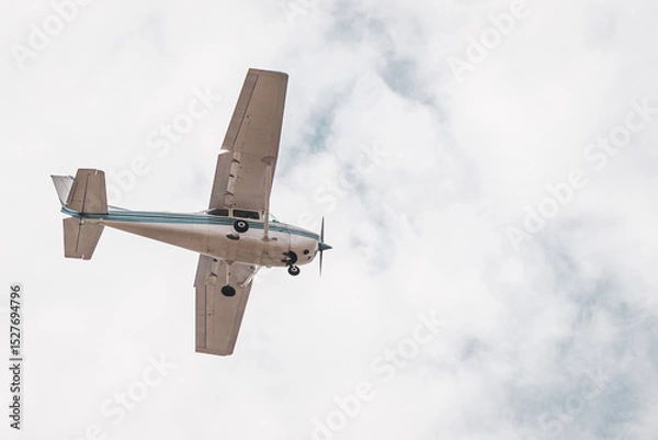 Fototapeta Private Airplane in Flight – Small Aircraft Landing or Taking Off in a Cloudy Blue Sky