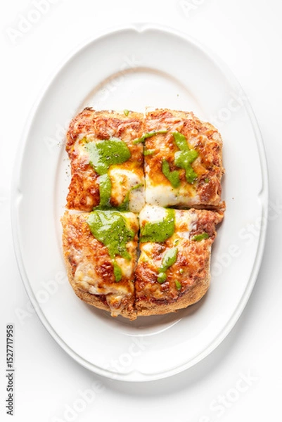 Fototapeta Close-up of a crispy Italian-style pizza bread topped with melted cheese, tomato sauce, and green pesto, served on a white plate. The vibrant colors and textures make it look appetizing and fresh