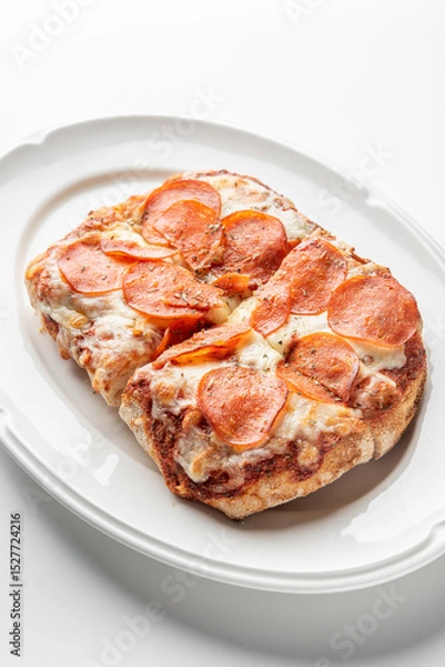 Fototapeta Close-up of a freshly baked pepperoni pizza slice with melted mozzarella cheese, sprinkled with herbs, served on a white plate. The crispy crust and rich tomato sauce enhance its appetizing appearance