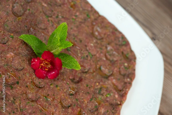Obraz Kebbe naye is showcased on a white plate, featuring finely chopped raw meat mixed with bulgur, onions, mint, and spices, designed for a rich culinary experience.