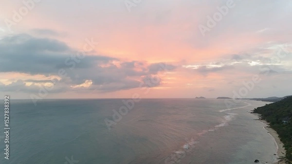 Fototapeta Beautiful cloudy red sunrise over sea with beach, waves and mountains in the background. Impressive structure texture in the sky