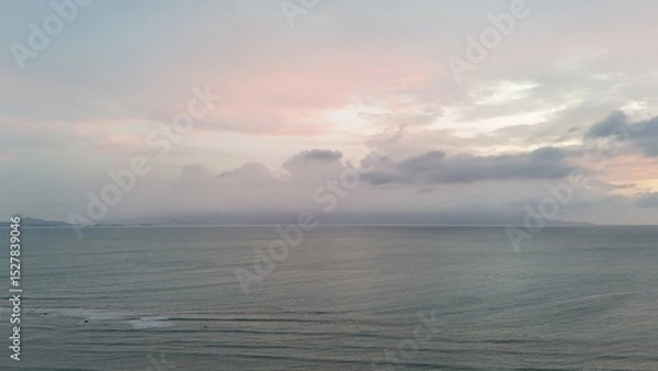 Fototapeta Beautiful cloudy red sunrise over sea with beach, waves and mountains in the background. Impressive structure texture in the sky