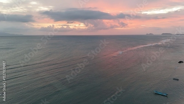 Fototapeta Beautiful cloudy red sunrise over sea with beach, waves and mountains in the background. Impressive structure texture in the sky