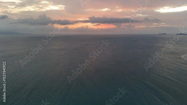 Fototapeta Beautiful cloudy red sunrise over sea with beach, waves and mountains in the background. Impressive structure texture in the sky