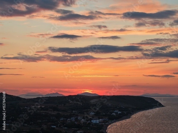 Fototapeta Beautiful cloudy red sunrise over sea with beach, waves and mountains in the background. Impressive structure texture in the sky