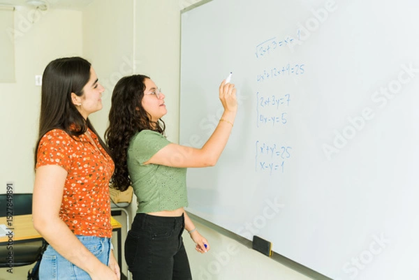 Obraz High school students solving math equations together on whiteboard
