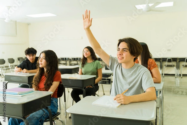 Obraz Hispanic high school student raising hand in classroom during lesson