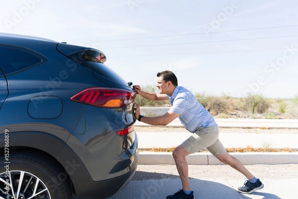 Obraz Frustrated driver pushing broken car on highway