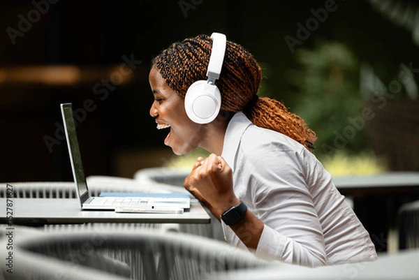 Obraz Beautiful black female freelancer working on laptop computer in cafe bar.