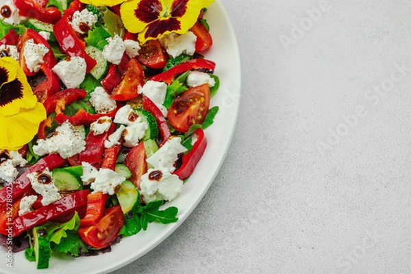 Obraz Fresh vegan salad with tomatoes, arugula, goat cheese, olives, and edible flowers on a white plate