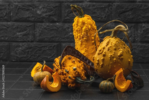 Obraz Organic ornamental pumpkins with textured skin and cut slices on dark background. Natural concept