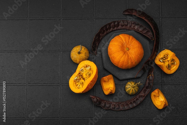 Obraz Organic ornamental pumpkins with textured skin and cut slices on dark background. Natural concept