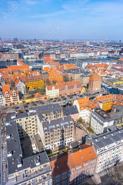 Fototapeta This aerial view captures the vibrant rooftops of residential buildings in Copenhagen, Denmark. Colorful facades contrast with the blue waters and sky, showcasing the city's charm and culture.