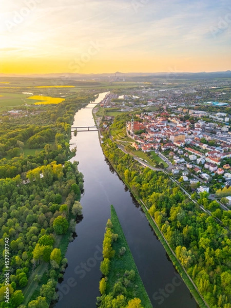 Fototapeta Aerial view reveals the beautiful confluence of the Vltava and Labe rivers close to Melnik, Czechia. Lush green banks and charming towns create a picturesque landscape during sunset.