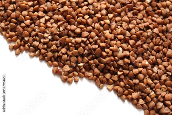 Obraz A pile of dry buckwheat lies on a white background.