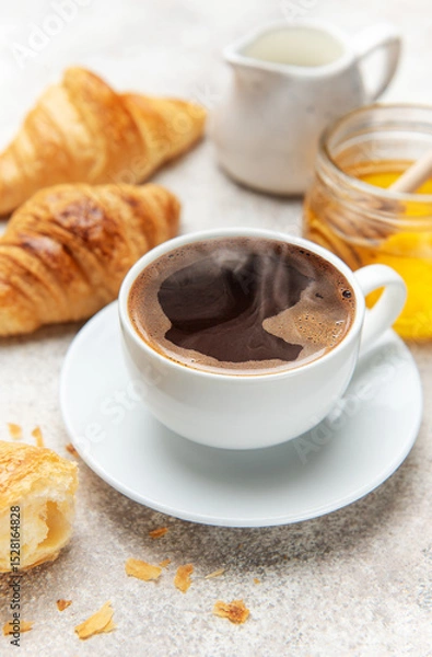 Fototapeta Steaming coffee, fresh croissants, and honey create a tempting breakfast scene