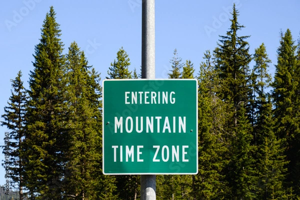 Fototapeta Rural sign with message in white text on green Entering Mountain Time Zone
