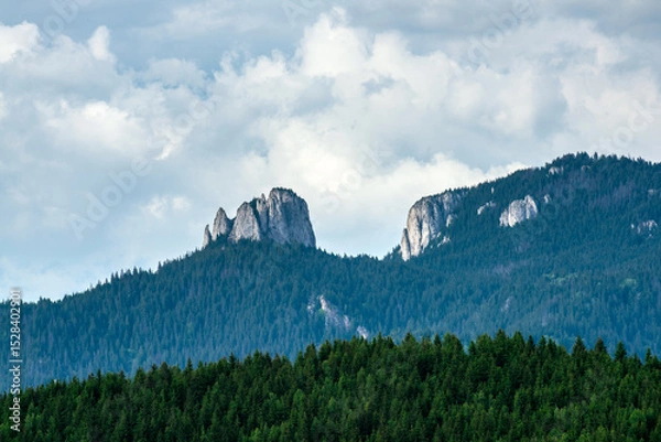 Fototapeta Egyeskő (Lonely Rock) Peak in Romania's Hagymás Nature Reserve, captured in high detail. Dramatic limestone cliffs under summer clouds, perfect for nature, hiking, and travel visuals.