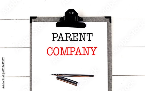 Fototapeta Parent company phrase on clipboard with pen on white wooden desk background