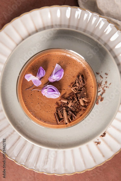 Obraz A very close overhead shot captures creamy chocolate mousse in a glass, perfectly garnished with chocolate shavings and purple flowers on decorative plates.