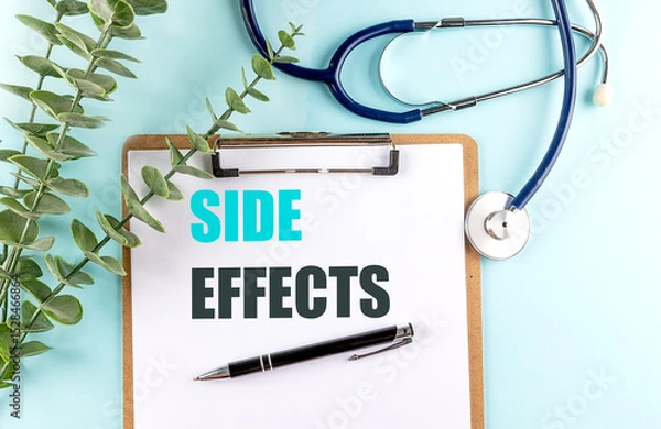 Fototapeta Side effects text on clipboard with pen, stethoscope and eucalyptus on blue background
