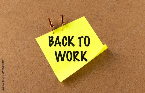 Fototapeta Back to work message on yellow sticky note pinned to corkboard with pushpins as motivational reminder
