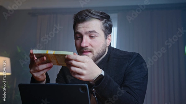 Obraz Excited man holding cash in front of laptop
