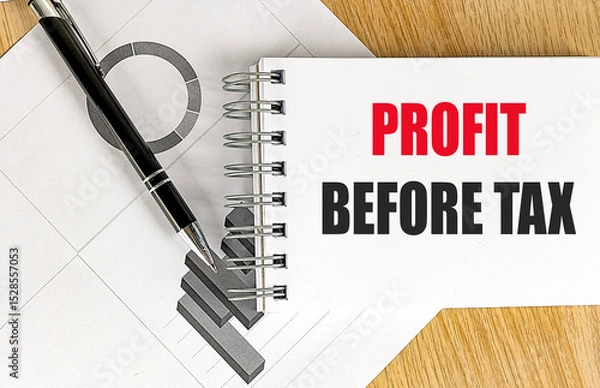 Fototapeta Profit before tax text on notepad with black pen and business charts on wooden desk