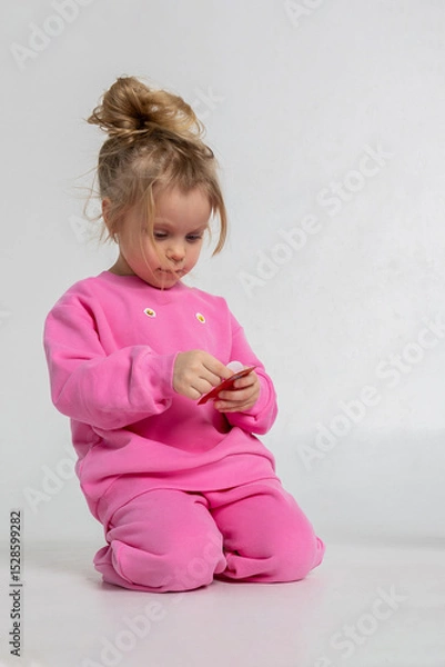 Obraz Portrait of cheerful playing girl. Child with smiles and funny emotions on light background. Vertical photo.