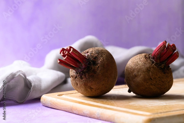 Obraz Fresh beetroot on cutting wooden board with purple background