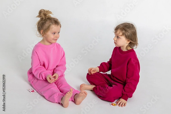 Obraz Two funny cute girls playing and having fun. Children with smiles and funny emotions on a light background