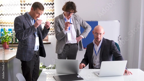 Fototapeta Three professional financiers are discussing the company's development strategy. Men in glasses and suits are working on a common project