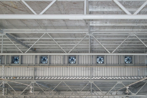 Fototapeta Row of ventilation fan on side wall under roof ceiling in factory warehouse. Attic insulation under roof sheet. Steel fan part of industrial building for heat air drain, air circulation. 