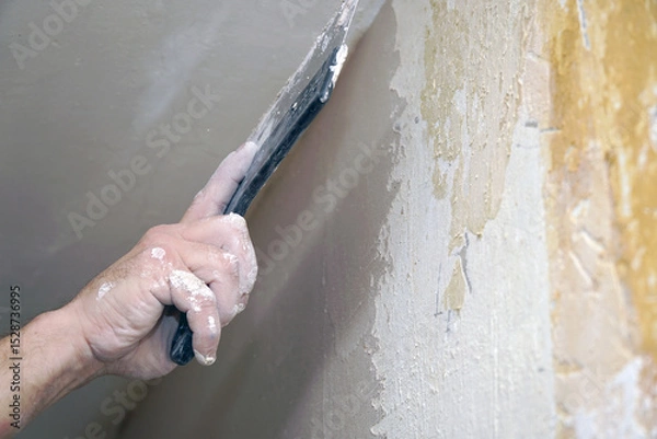 Obraz A man plastering a wall with a spatula