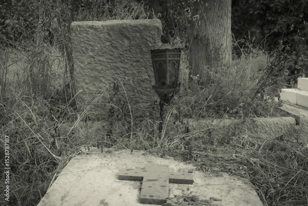 Fototapeta Black and white photo of an old grave with an old lamp  in cemetery.