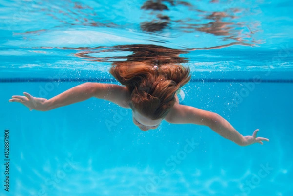 Fototapeta Underwater child swims in pool, healthy child swimming and having fun under water.