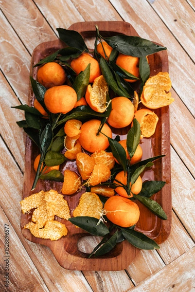 Fototapeta Ripe tangerines on the background of a wooden table. Assembled juicy tangerine in close-up. Delicious citrus fruits for juicing
