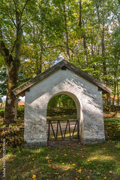 Obraz Old idyllic churchgate by a country road in a forest at autumn
